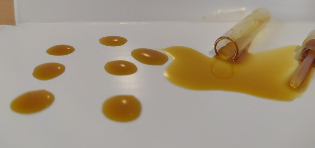 gotas de aceite de cbd derramadas sobre una mesa blanca