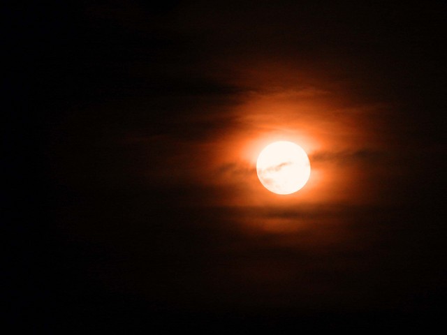 Luna llena y roja sobre un cielo con alguna nube
